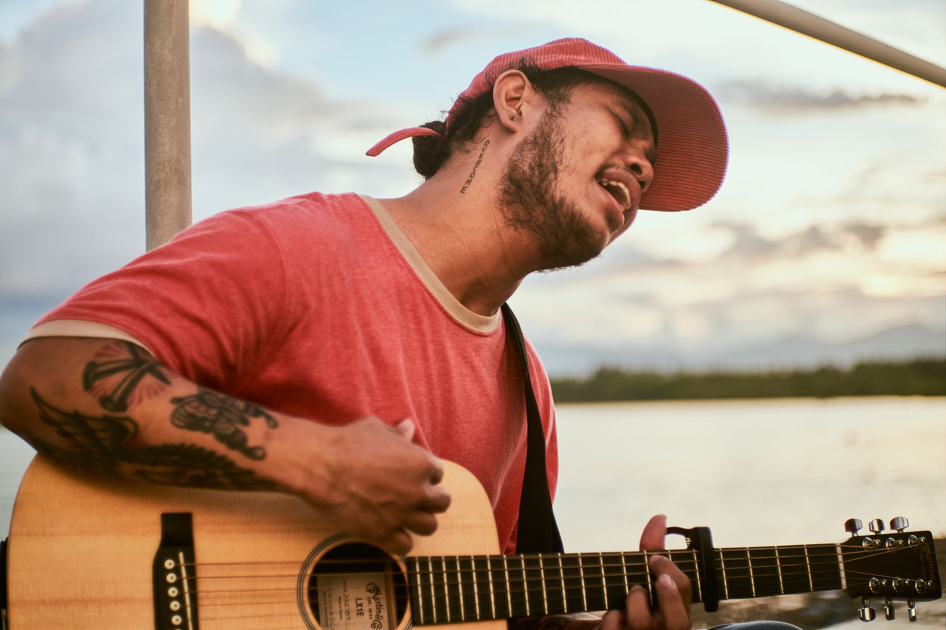 Mężczyzna śpiewa i gra na gitarze akustycznej o zachodzie słońca