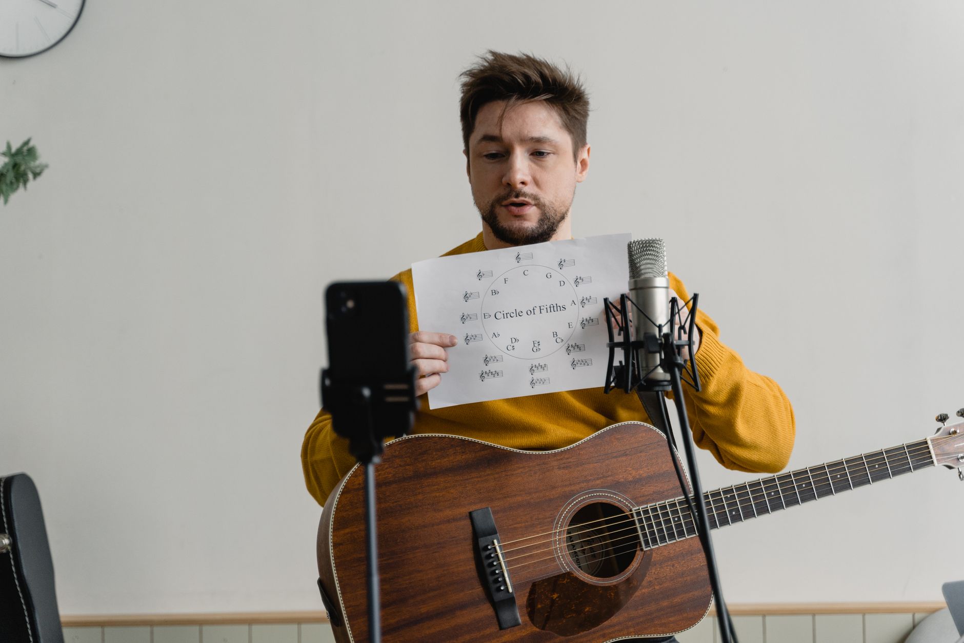 Mężczyzna z gitarą akustyczną tłumaczy teorię akordów online